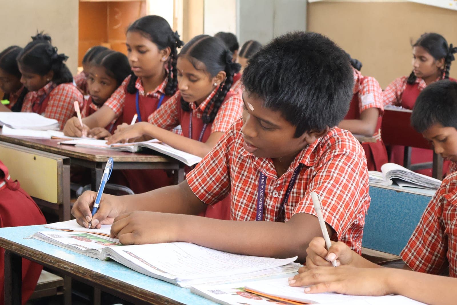 Children writing at their desks in a CMCT-supported classroom