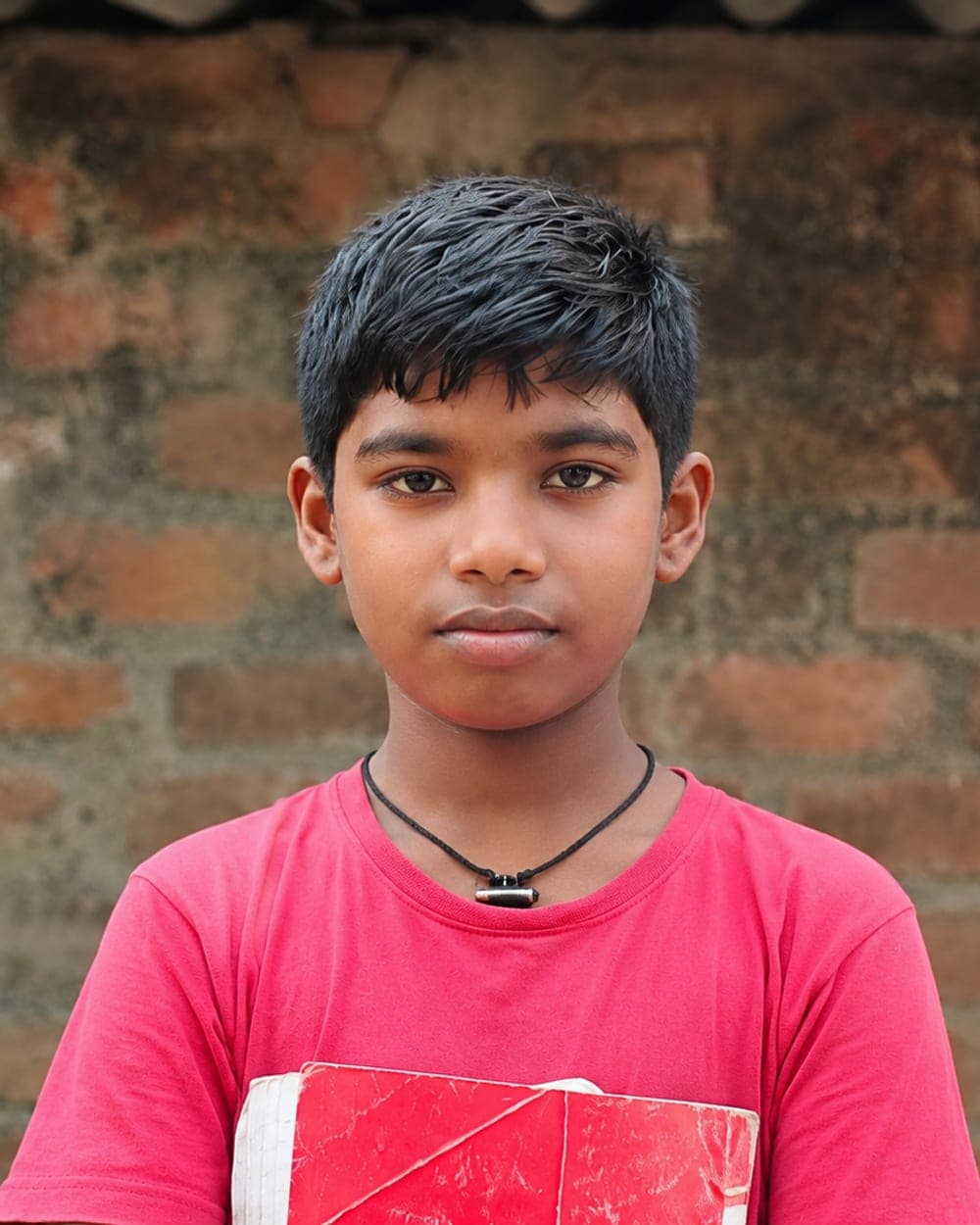 Krithick Adithya, a CMCT-supported student, holding his schoolbook